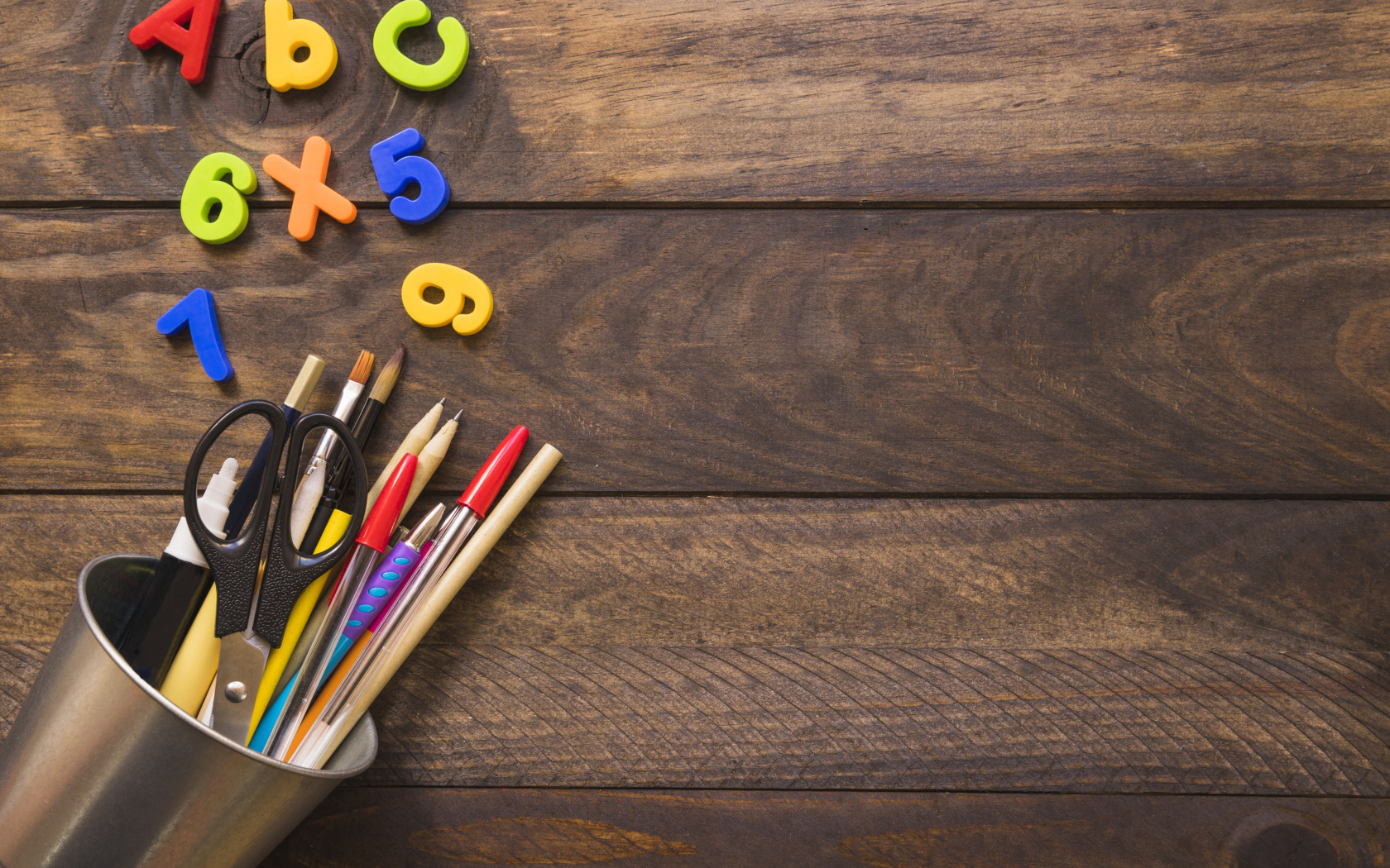 Банка с канцелярскими принадлежностями на деревянном столе с цифрами