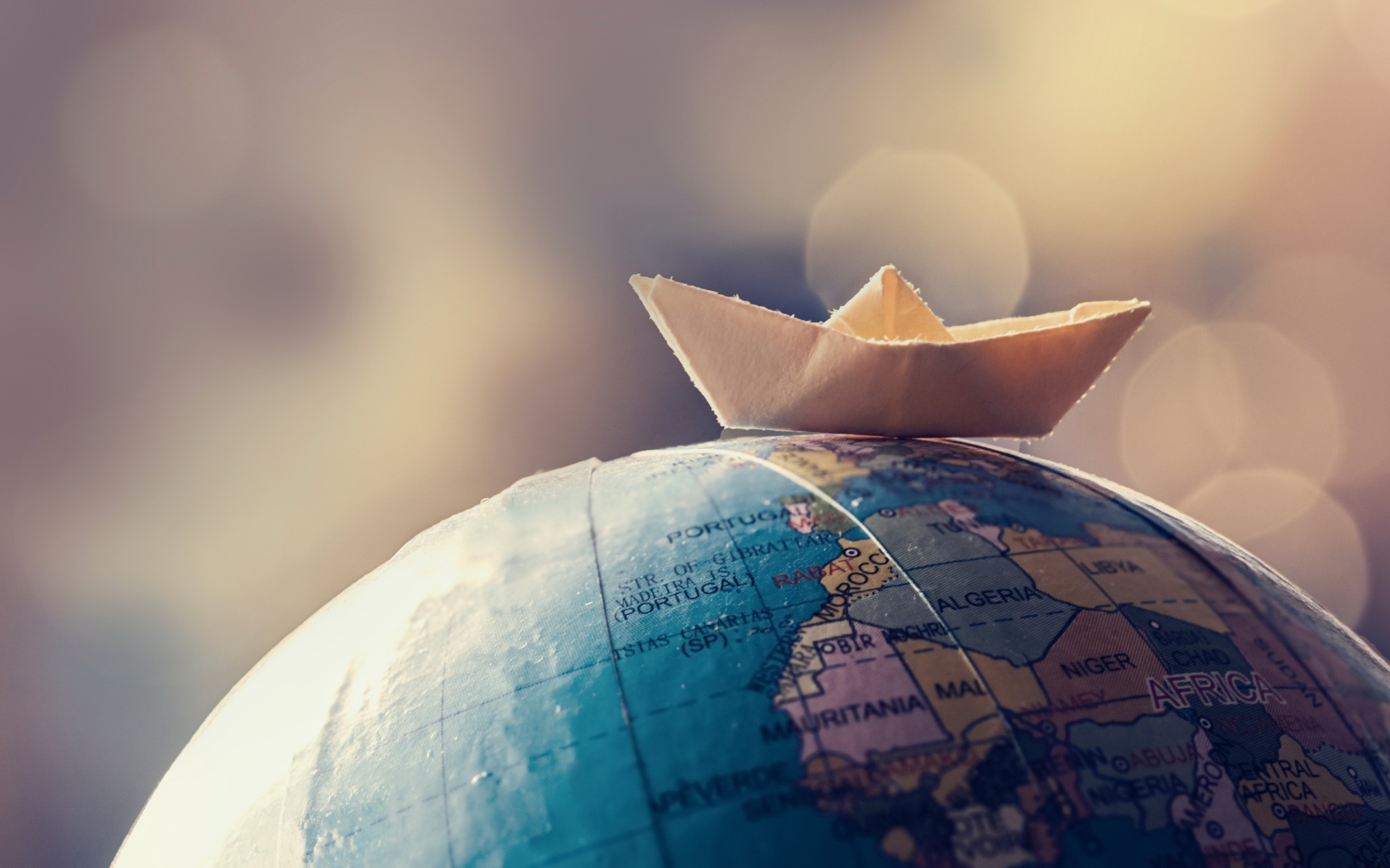 Бумажный кораблик лежит на глобусе