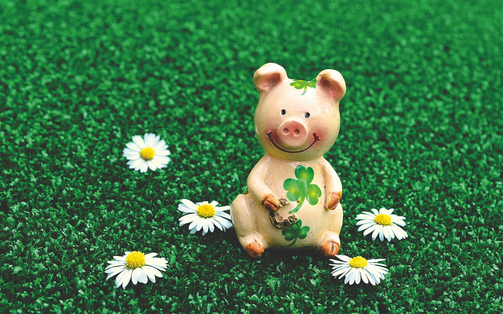 Статуэтка поросенка на зеленой траве с ромашками