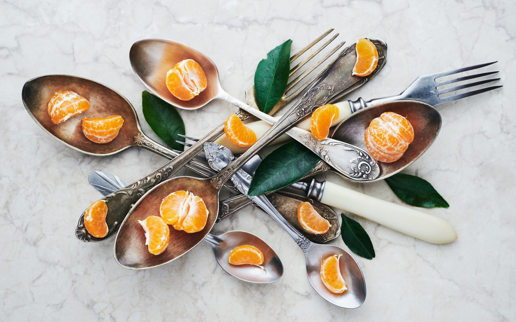 Столовые приборы на столе с дольками мандарина