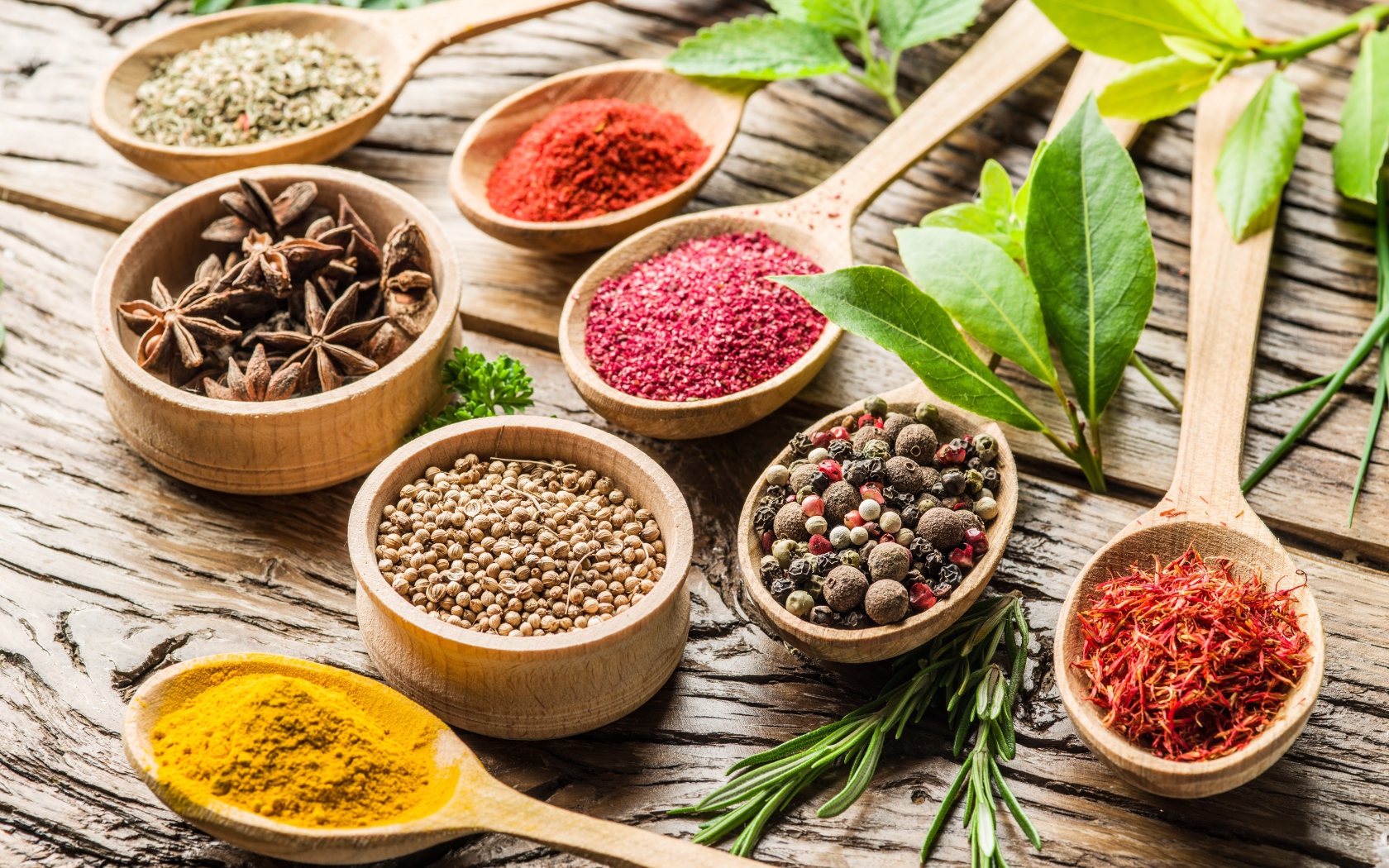 Разные специи в деревянных ложках на столе 