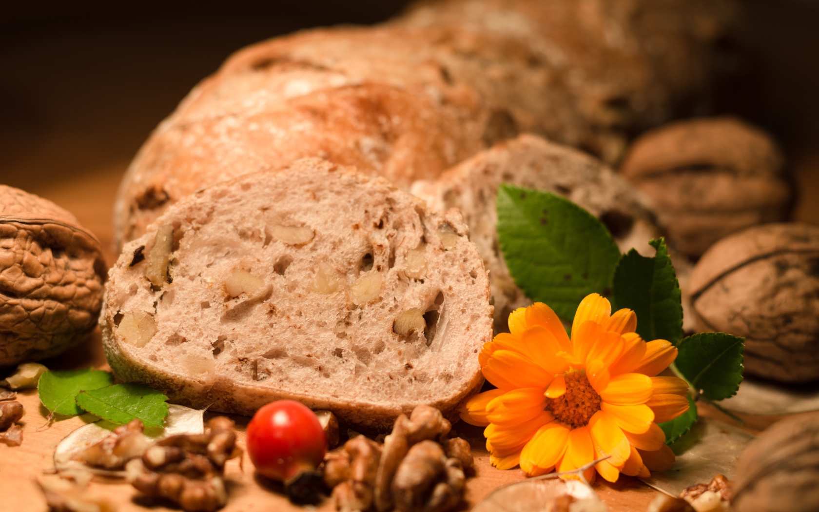 Свежий хлеб с грецкими орехами и цветами календулы на столе