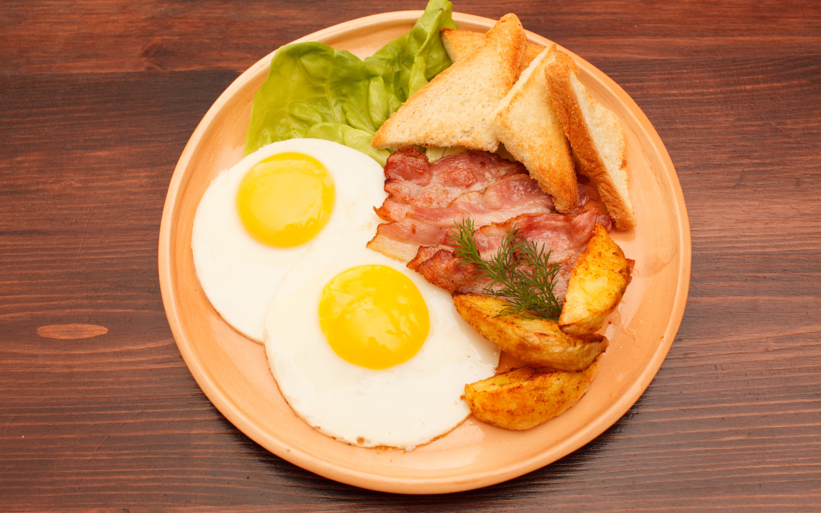 Fried eggs with bacon, french fries and croutons on the table