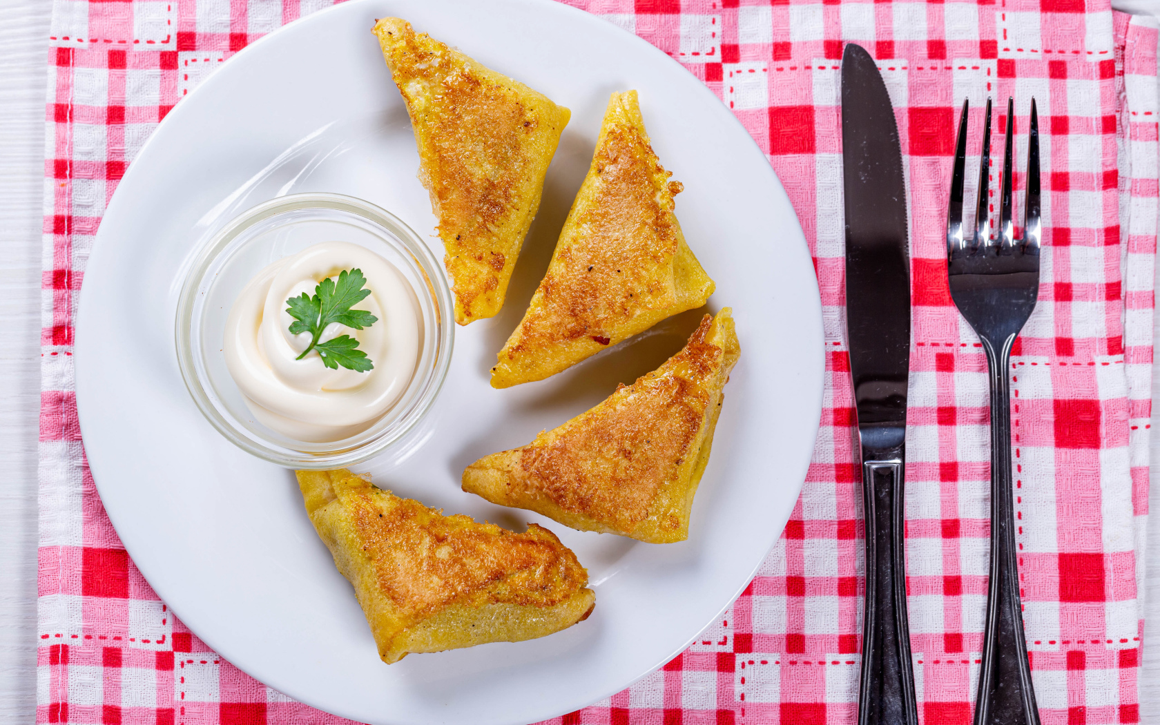 Блинчики со сметаной на столе со столовыми приборами 