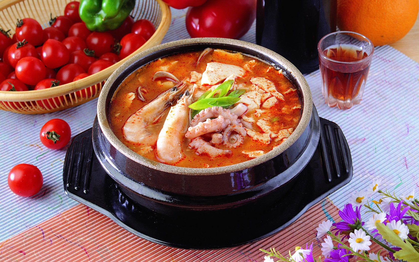 Тарелка красного супа с морепродуктами на столе с овощами 