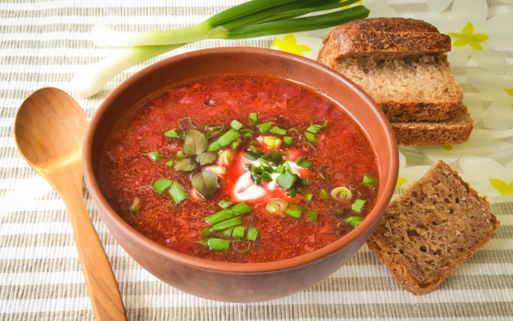 Красный борщ с луком на столе с хлебом 