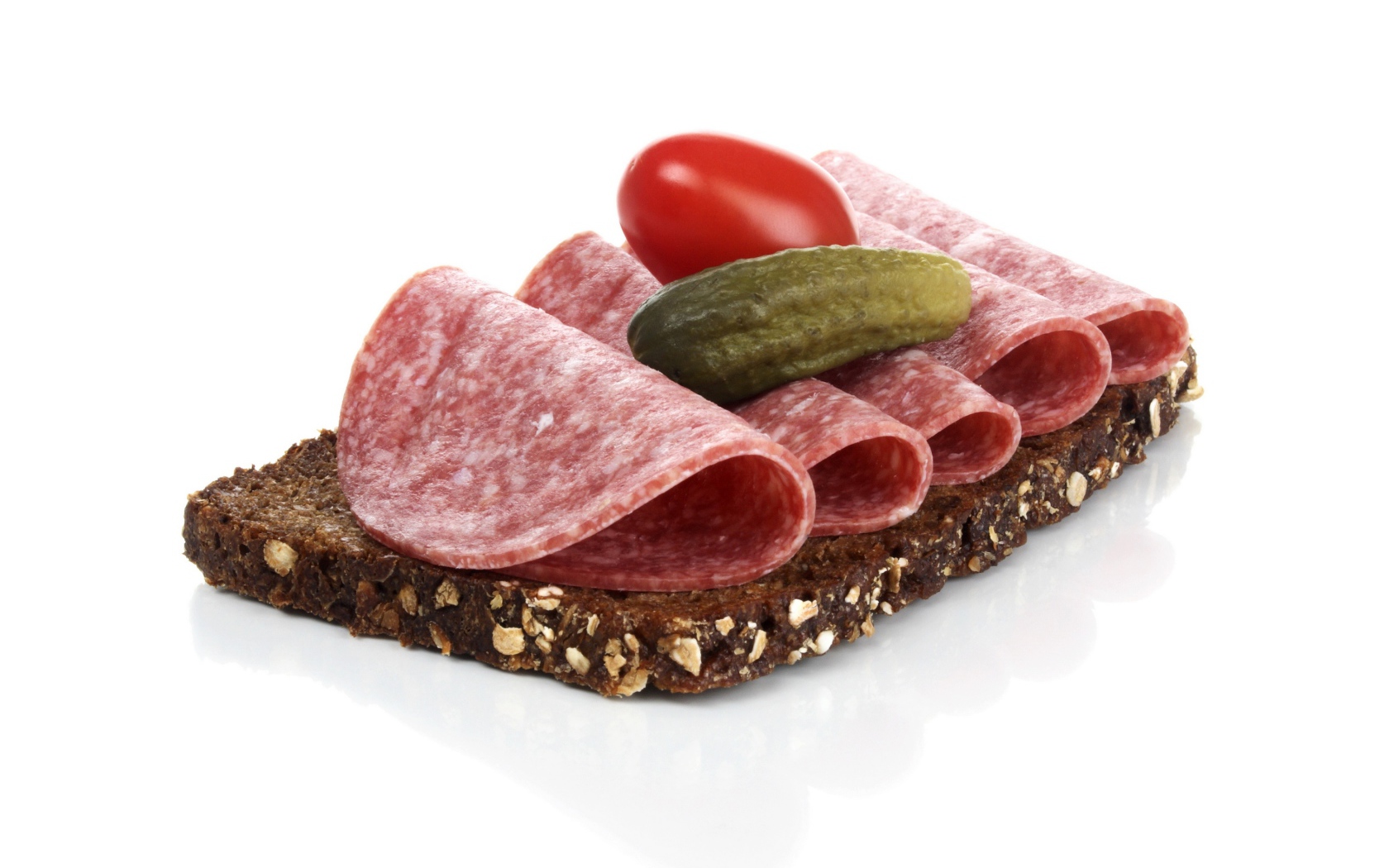 Бутерброд с черным хлебом, колбасой, соленым огурцом и помидором на белом фоне