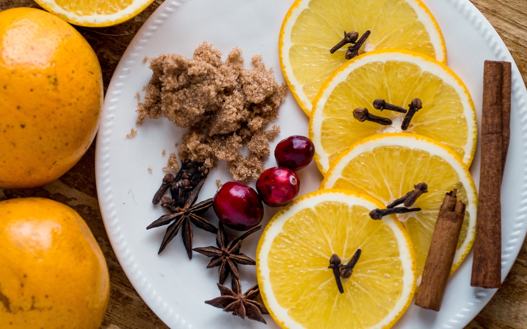 Круги апельсина на тарелке с сахаром, корицей и бадьяном