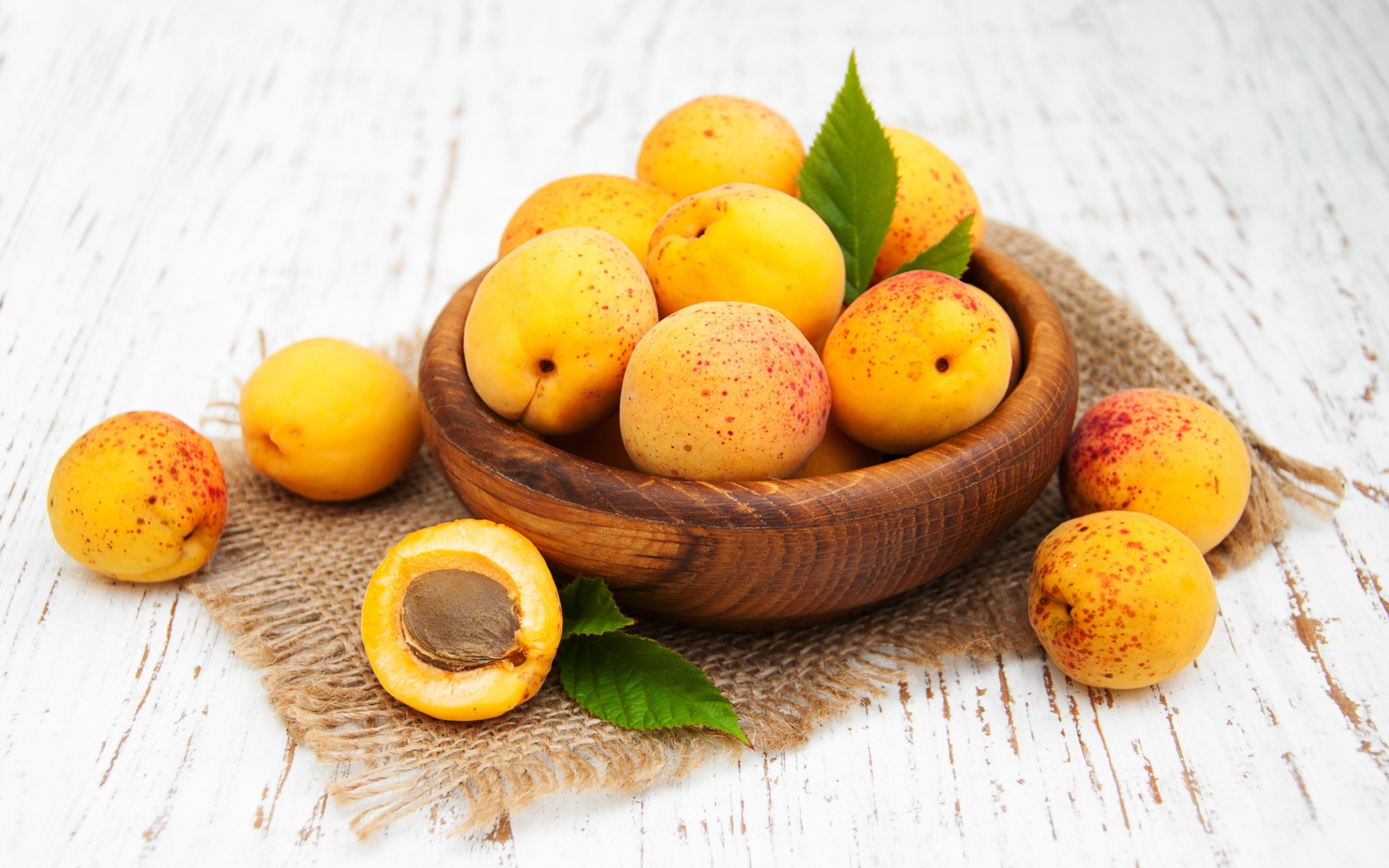 Спелые абрикосы в деревянной миске на столе