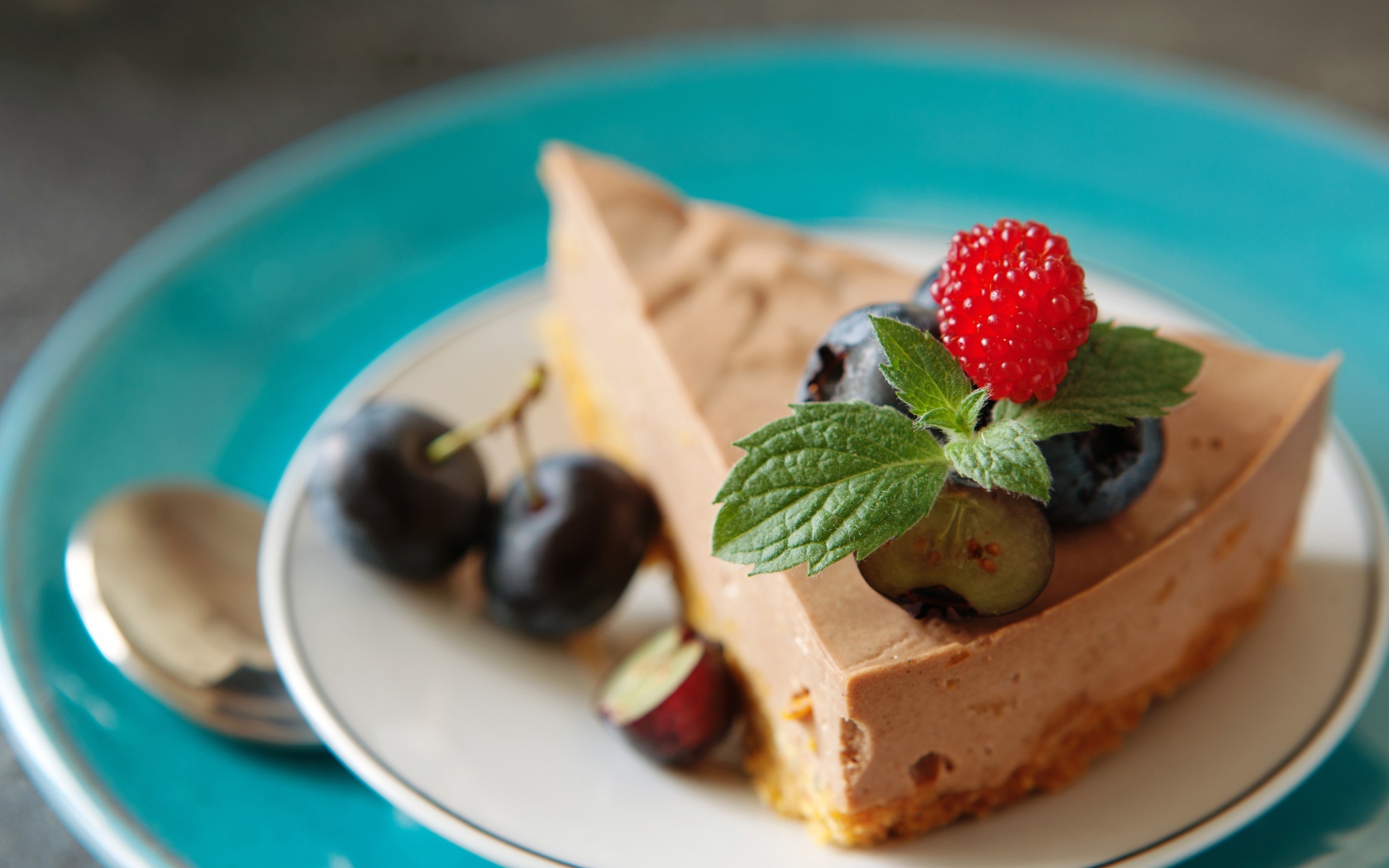 Кусок чизкейка на тарелке с ягодами черники и малиной