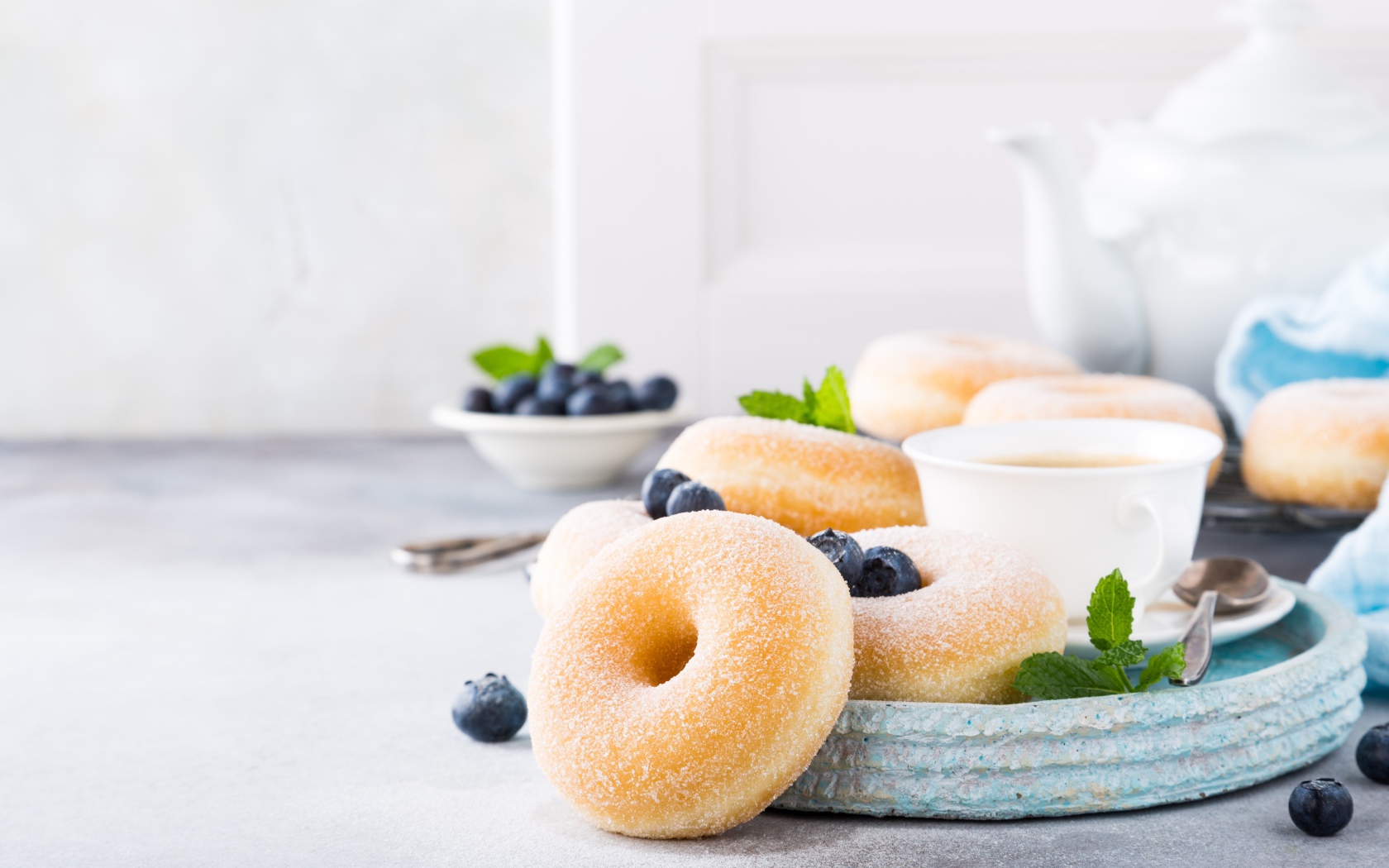 Аппетитные пончики с сахарной пудрой на столе с черникой