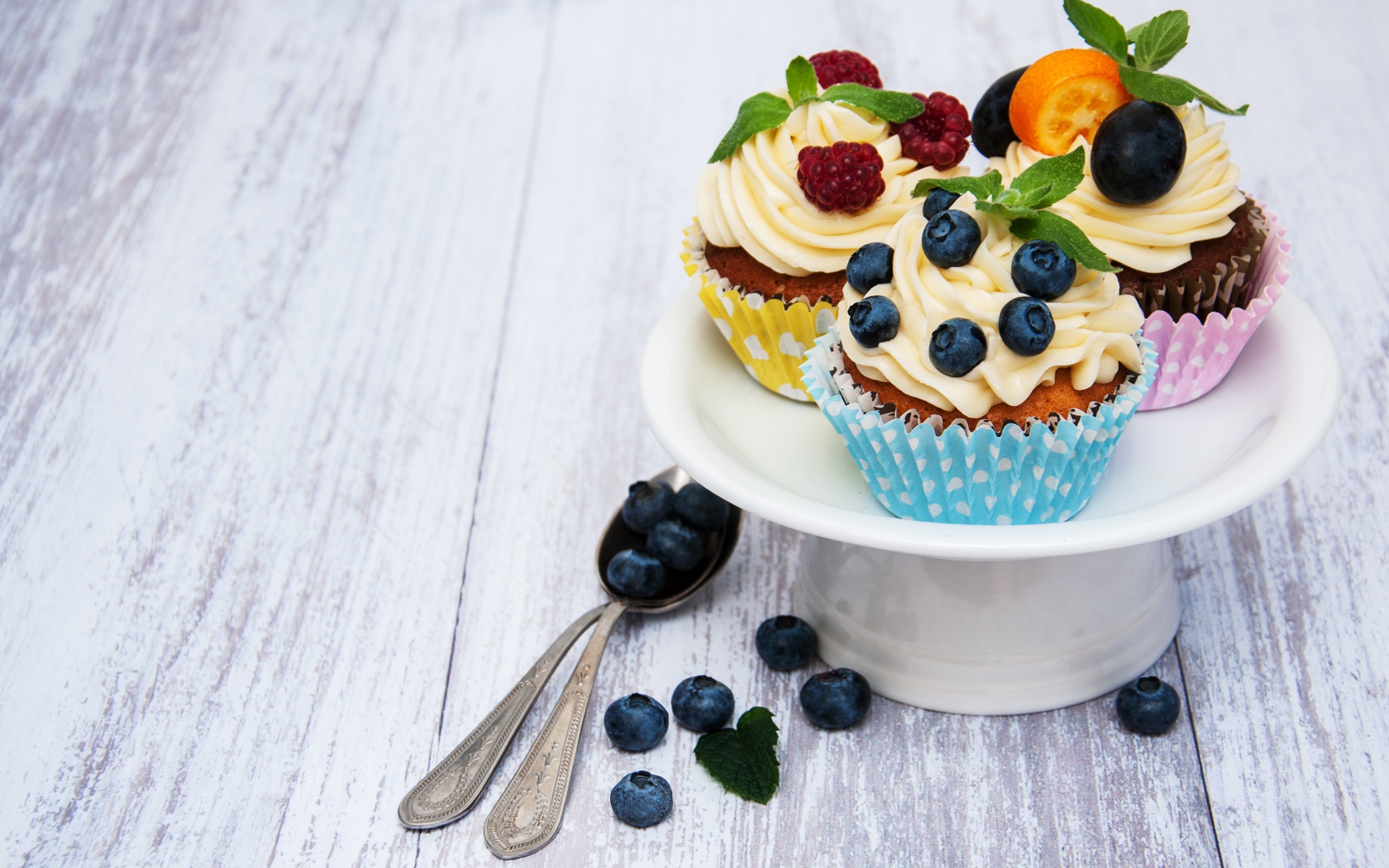 Кексы с кремом на белом блюде с ягодами