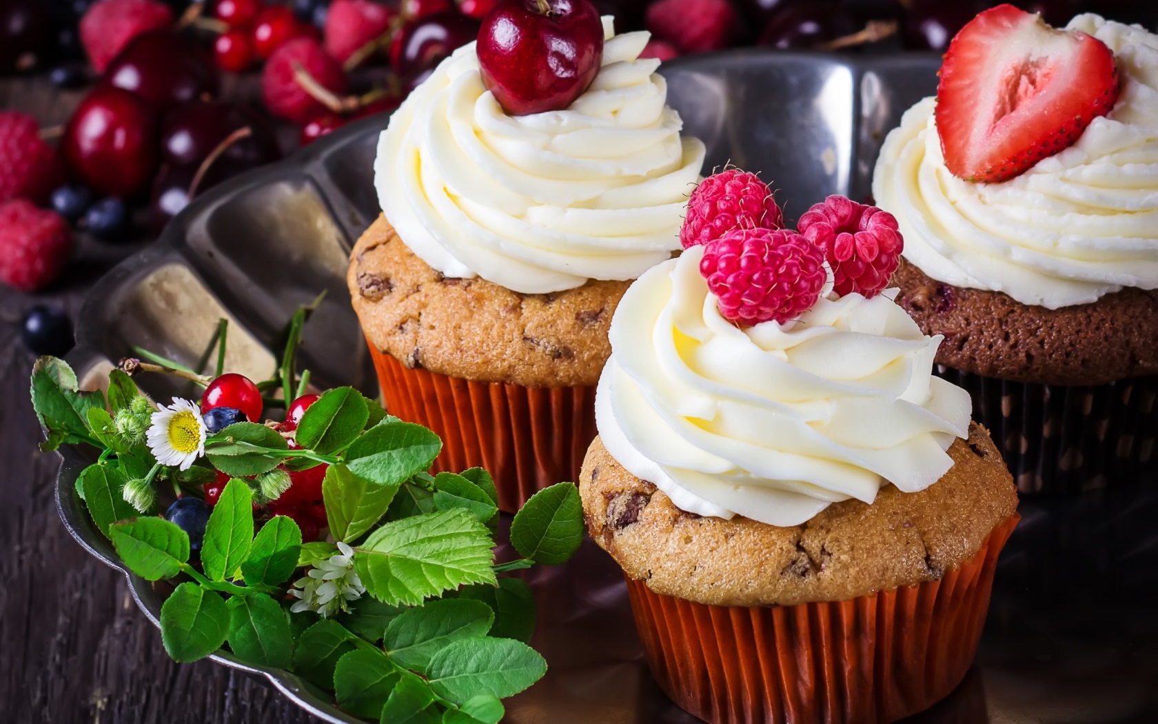 Аппетитные кексы с кремом и ягодами на блюде