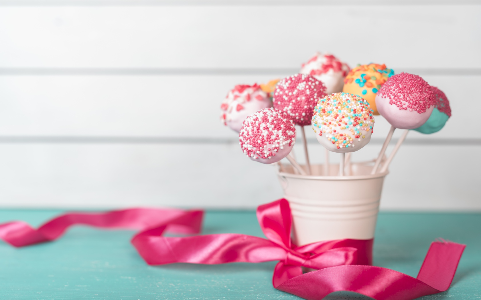 Леденцы в стакане на столе с розовым бантом из ленты