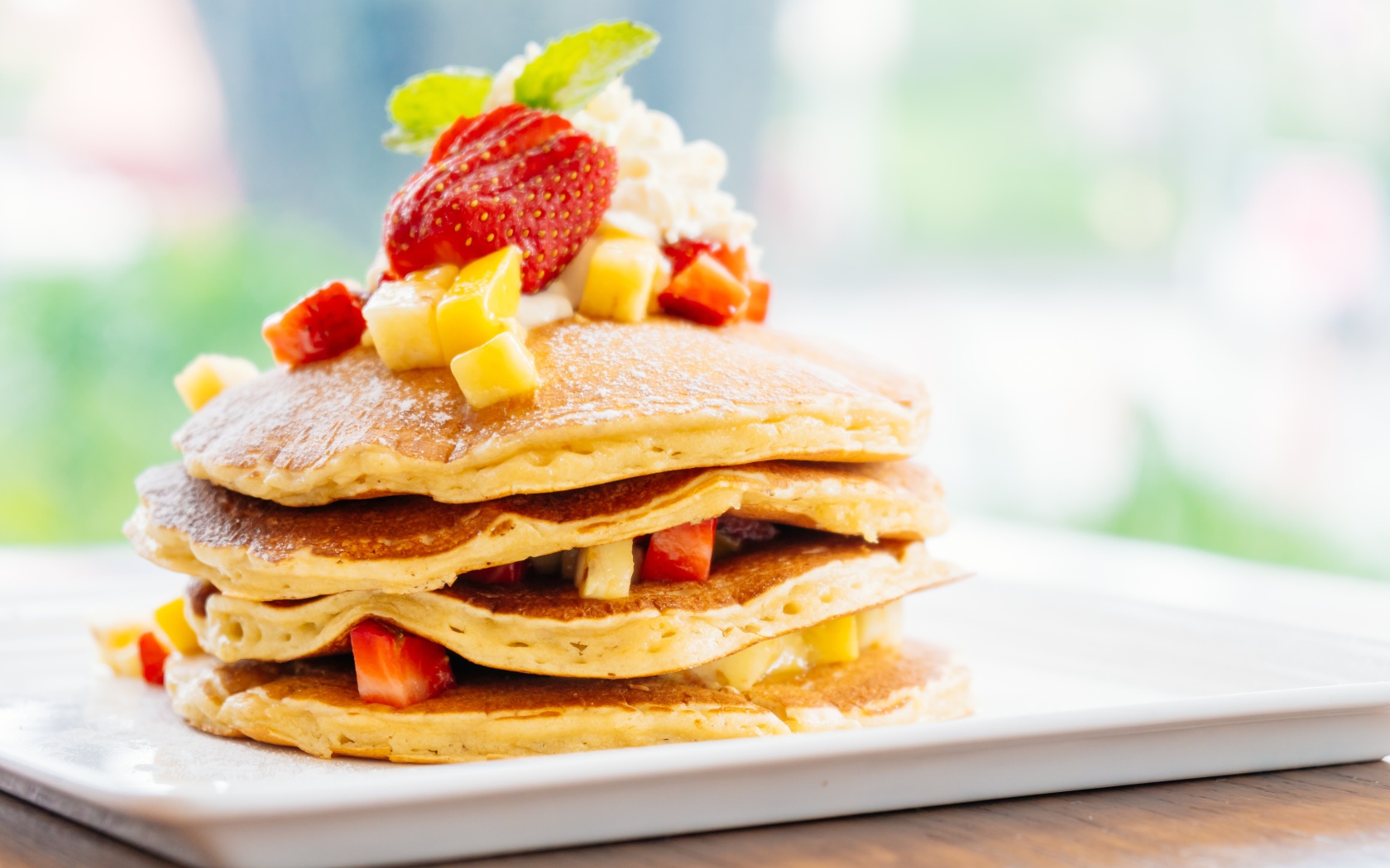 Оладьи с сахарной пудрой, сливками и кусочками клубники и ананаса