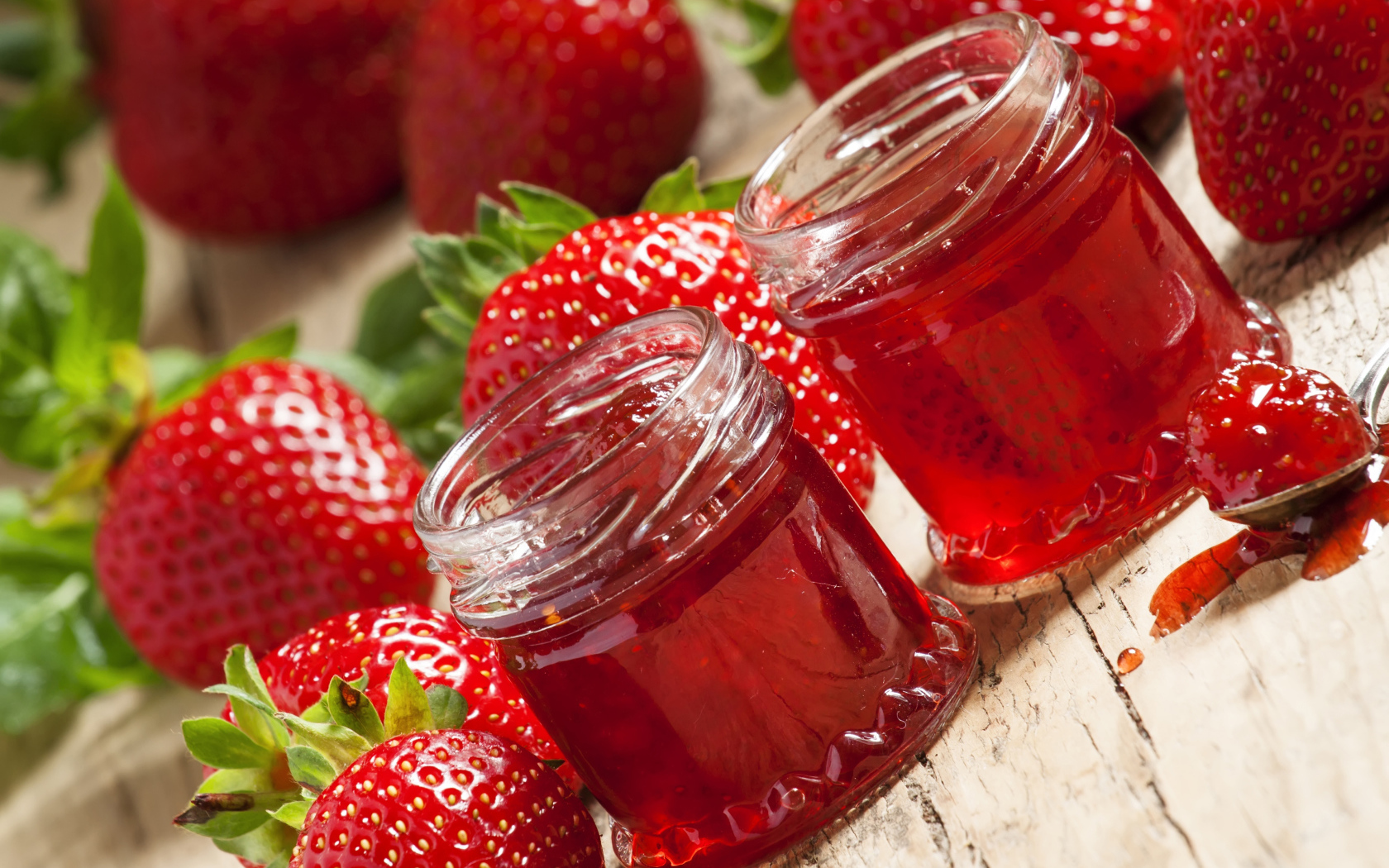 Две баночки клубничного джема на столе с клубникой