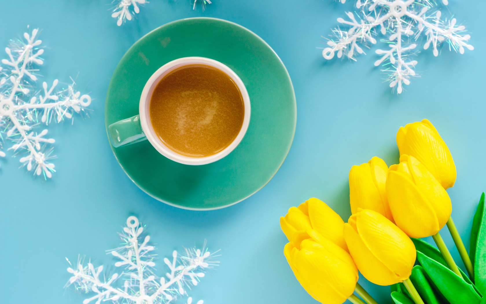 Чашка кофе на голубом фоне со снежинками и букетом желтых тюльпанов