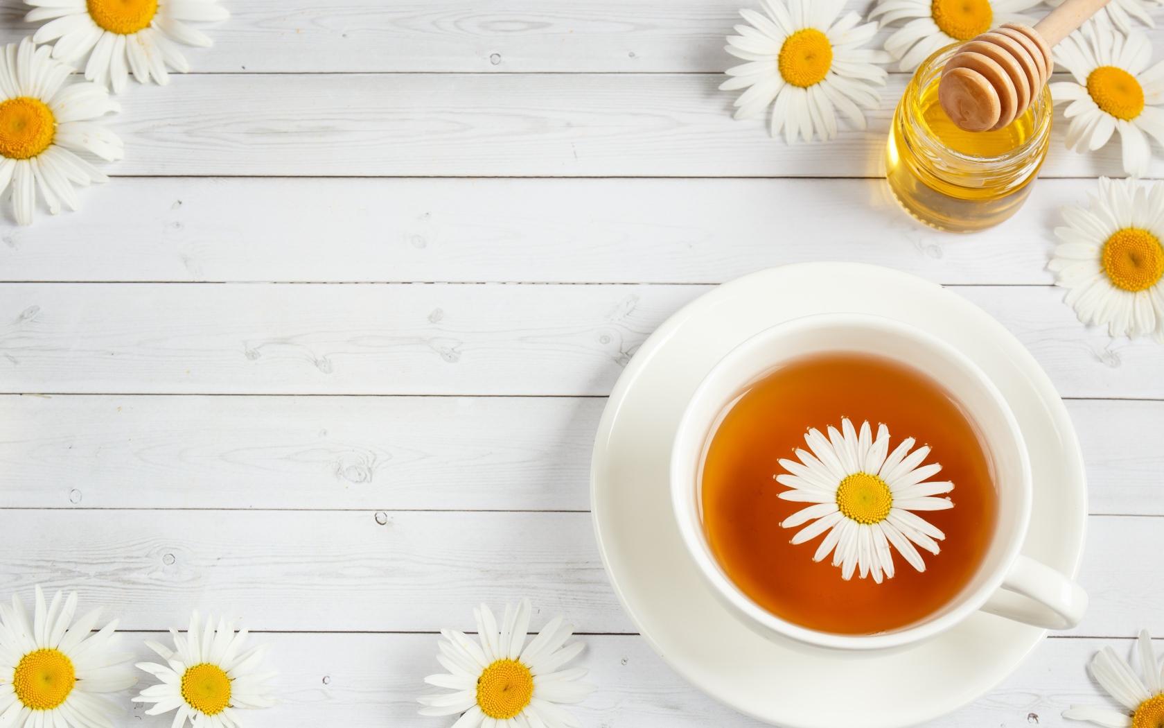 Чашка чая с ромашкой на столе с медом