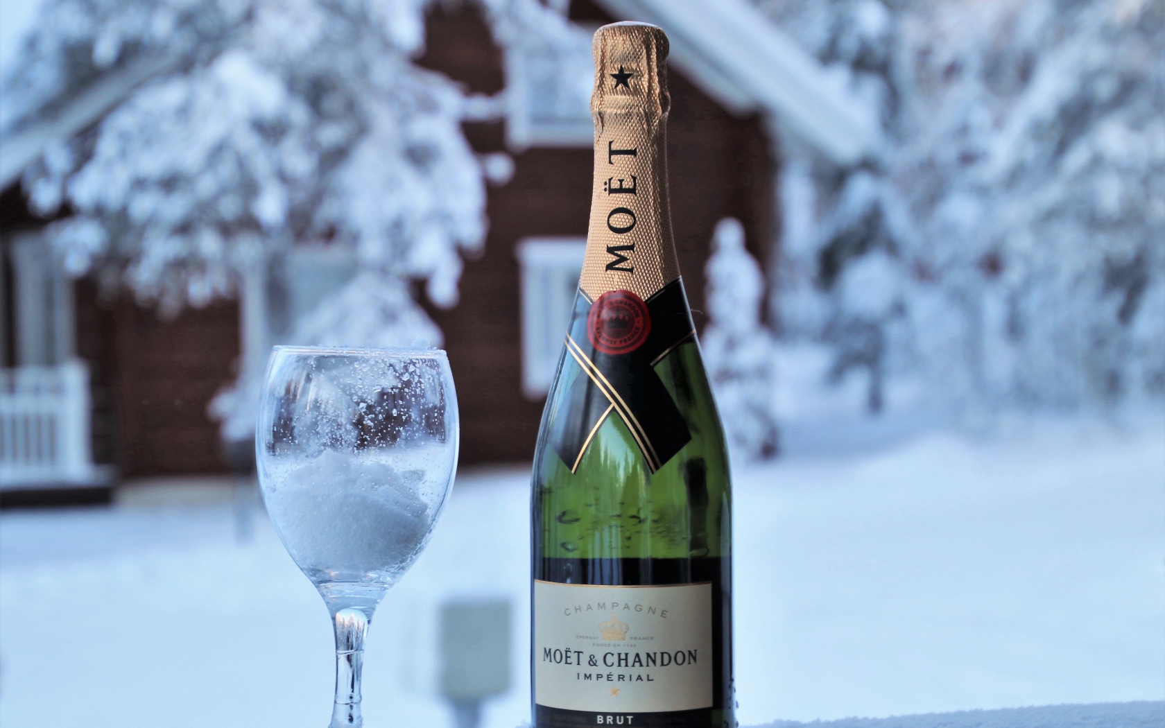 Бокал на снегу с бутылкой шампанского 