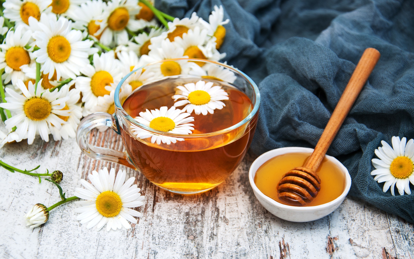 Чашка чая на столе с медом и букетом ромашек
