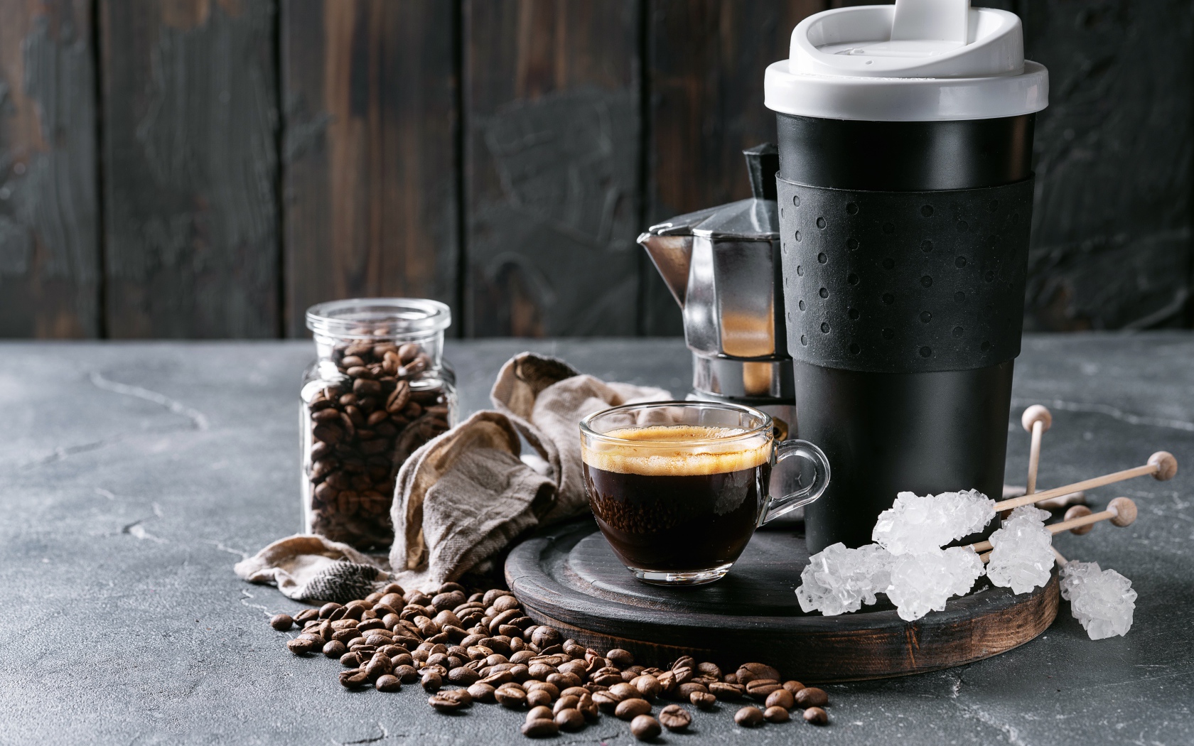 Стеклянная чашка кофе на столе с термосом и зернами