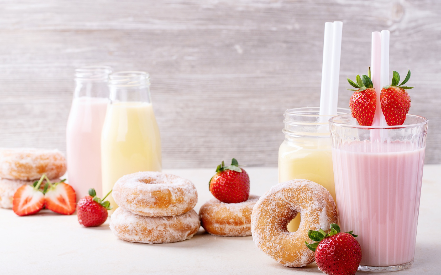 Молочные коктейли на столе с клубникой и пончиками