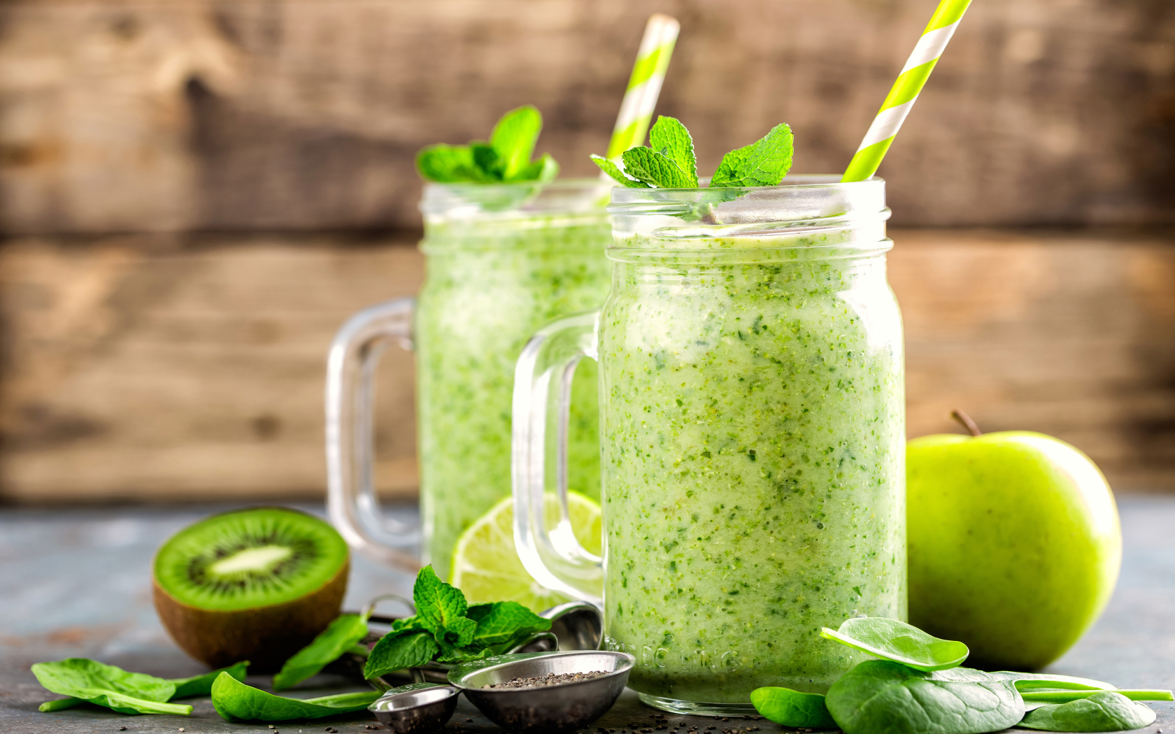 Два зеленых смузи на столе с киви, мятой и зеленым яблоком