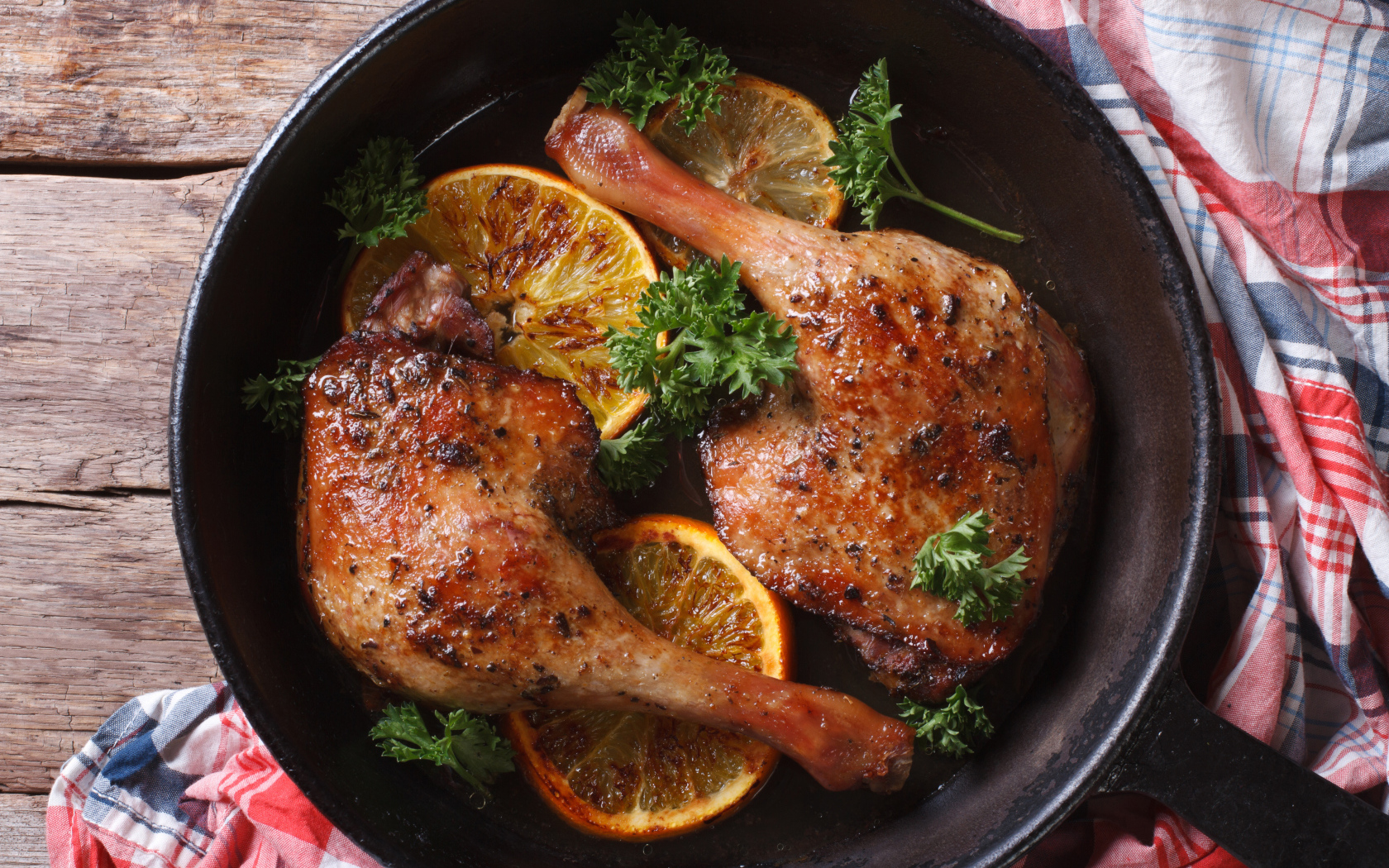 Куриные окорочка в сковороде с кольцами апельсина и петрушкой