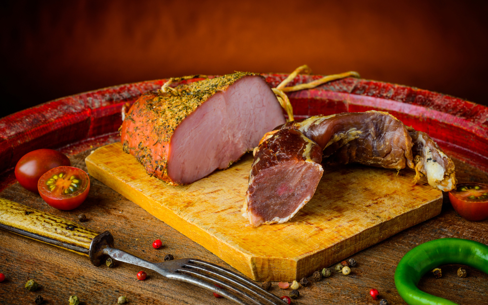 Ветчина и вяленое мясо на разделочной доске на столе с помидорами и горьким перцем 