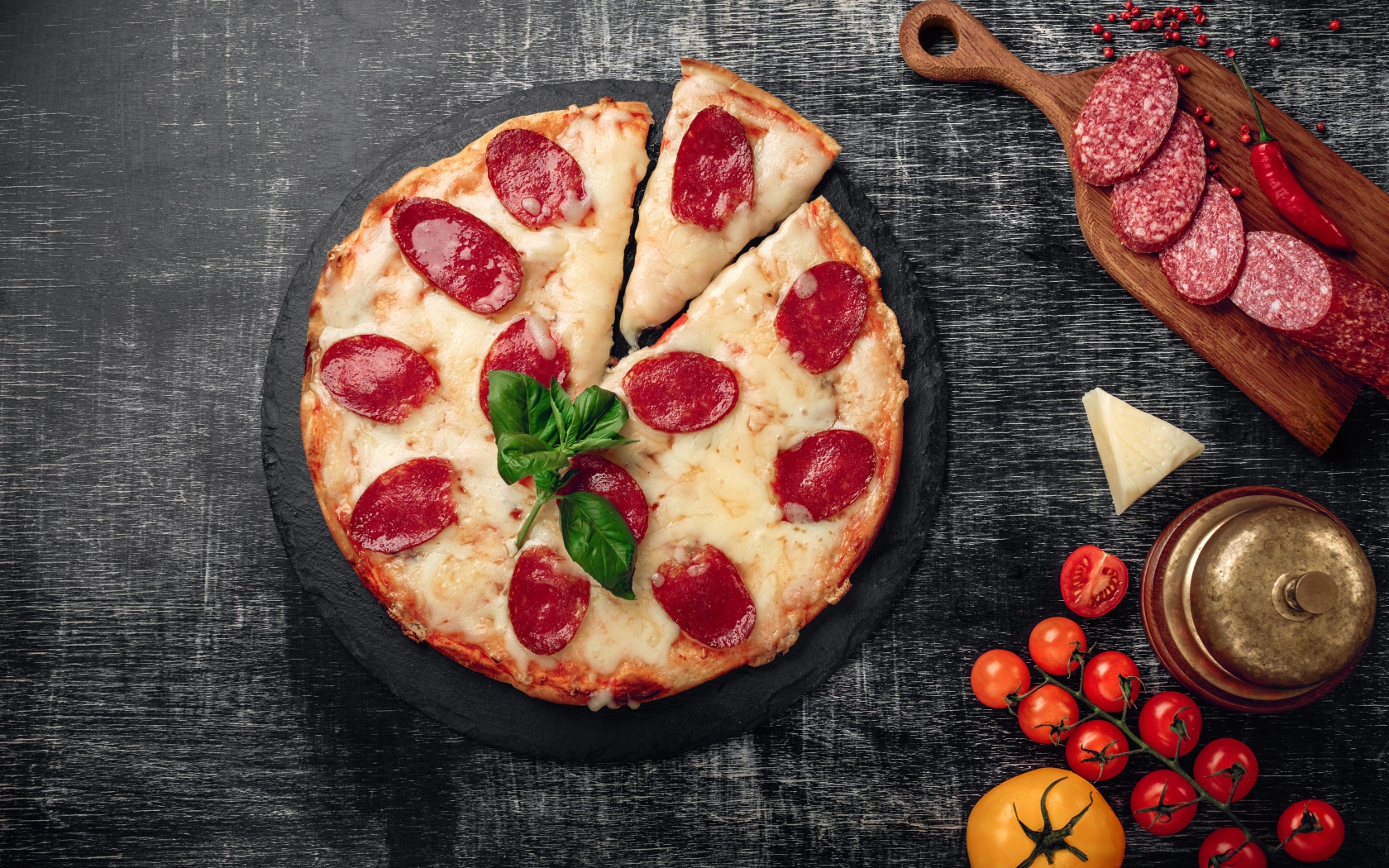 Пицца с сыром и салями на столе с помидорами и колбасой