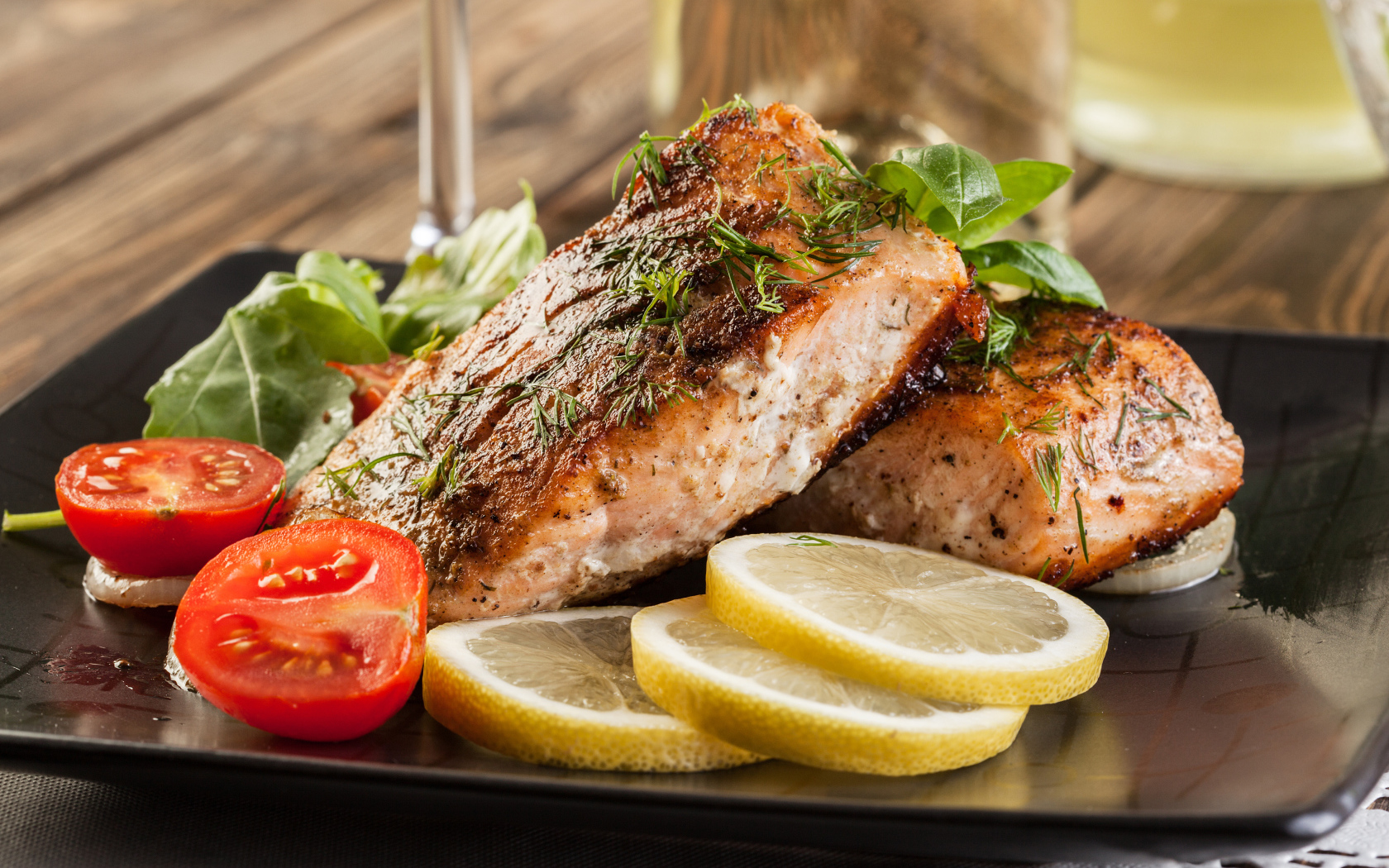 Куски запеченной рыбы на тарелке с помидорами и лимоном