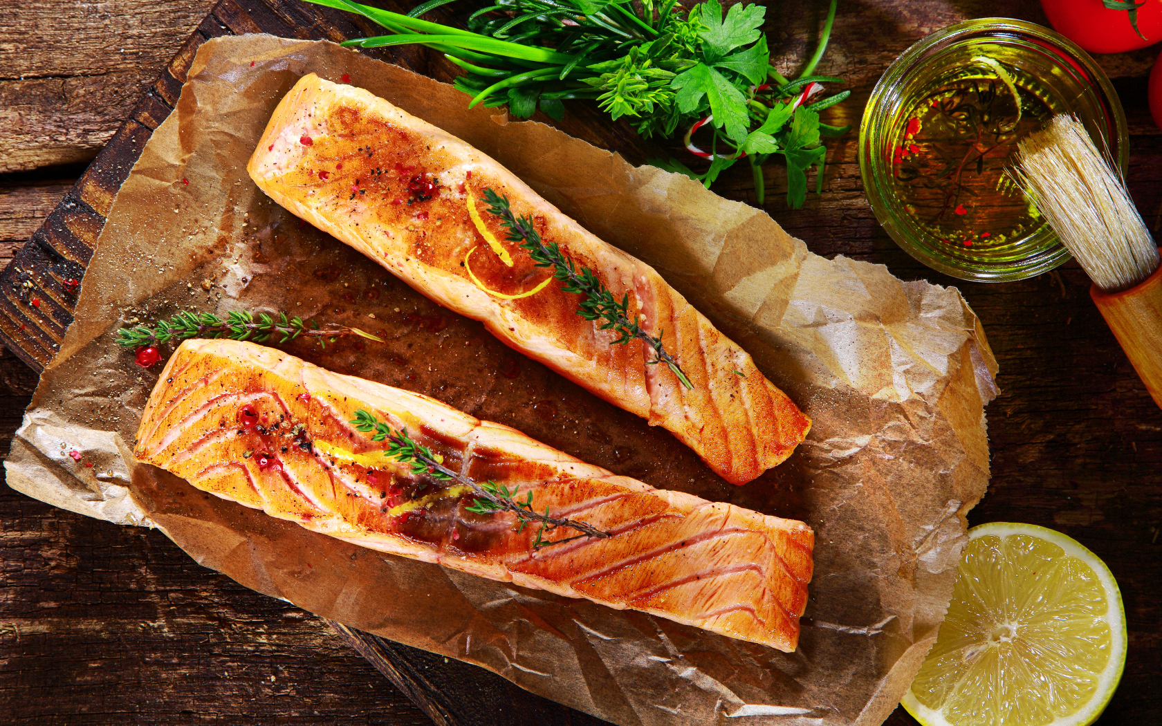 Два куска запеченной рыбы на столе с оливковым маслом и зеленью