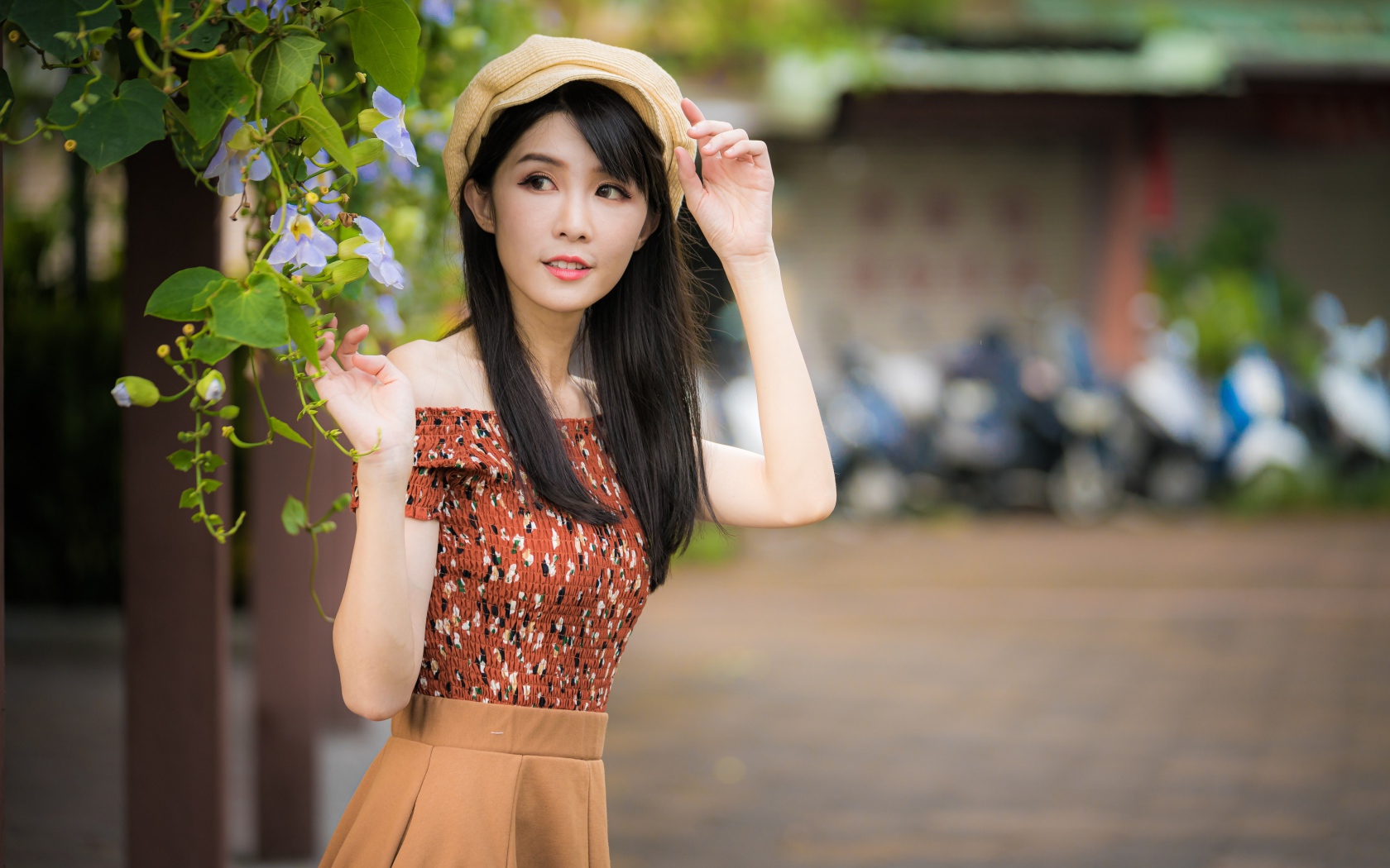 Молодая девушка азиатка в кепке стоит у голубых цветов