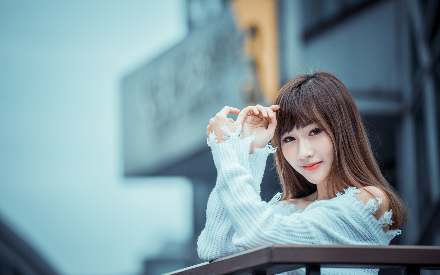 Молодая девушка азиатка в белом свитере на балконе