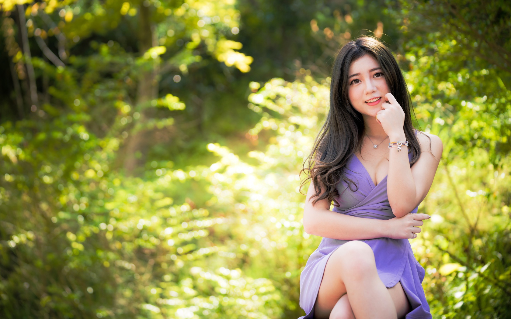 Молодая девушка азиатка сидит на лавке в парке