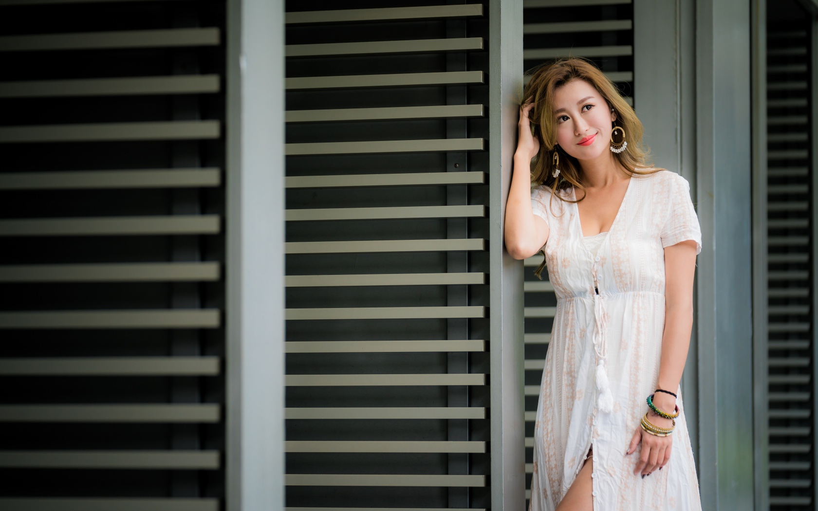 Красивая девушка азиатка в платье стоит у дверей