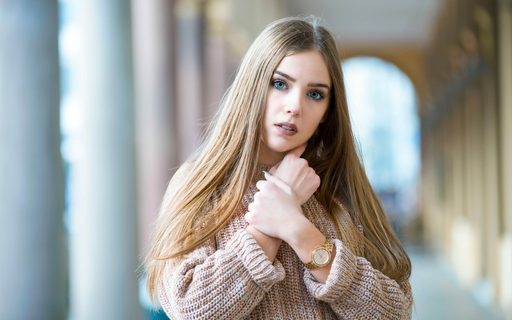 Красивая голубоглазая блондинка в теплом свитере с часами на руке