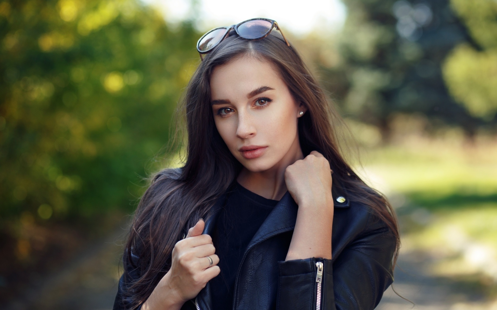 Красивая девушка в черной куртке с очками на голове