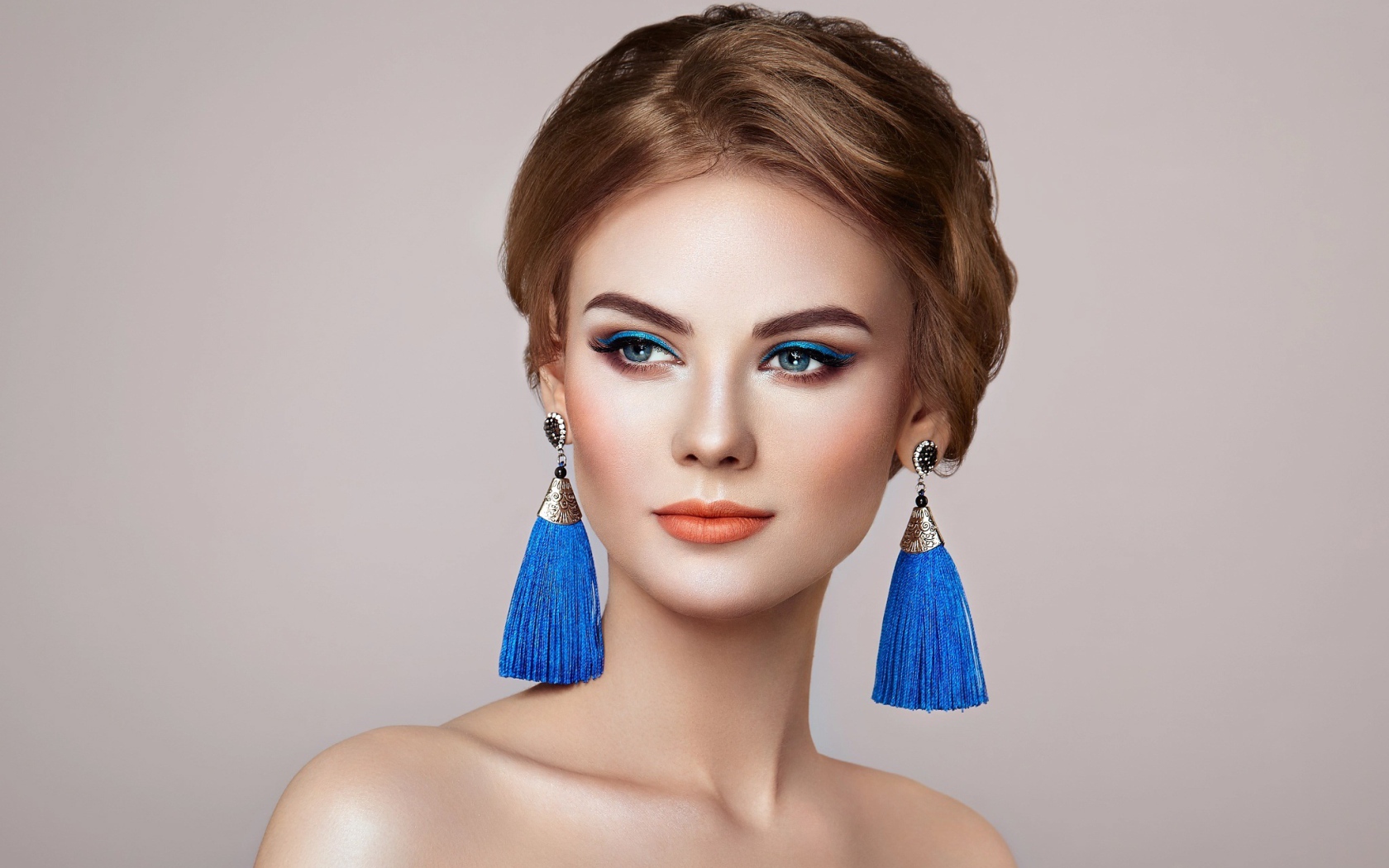 Красивая девушка с синими сережками на сером фоне