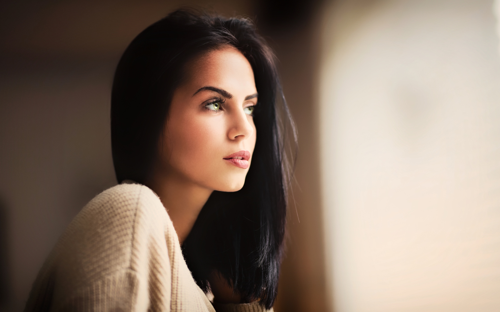 Красивая девушка зеленоглазая смотрит в окно 