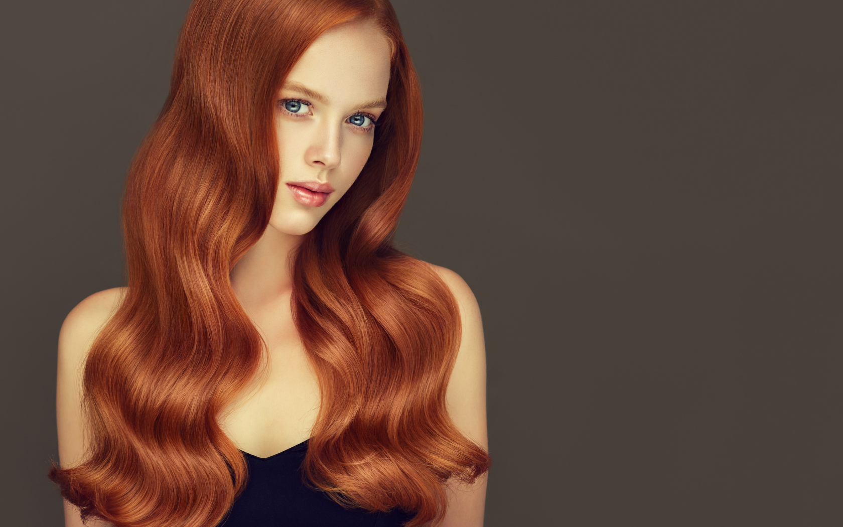 Красивая рыжеволосая голубоглазая девушка на сером фоне