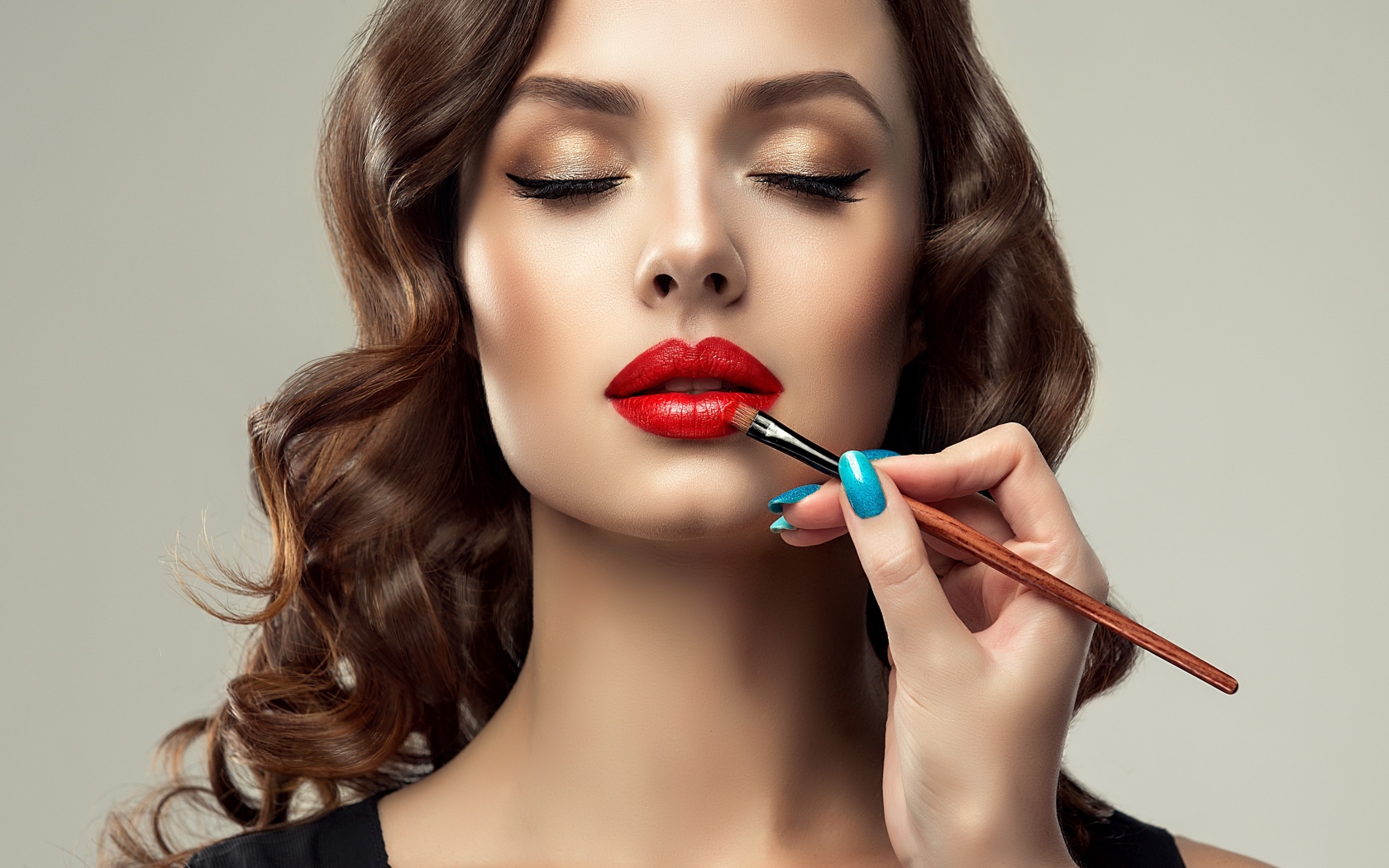 Красивой молодой девушке с закрытыми глазами делают макияж 