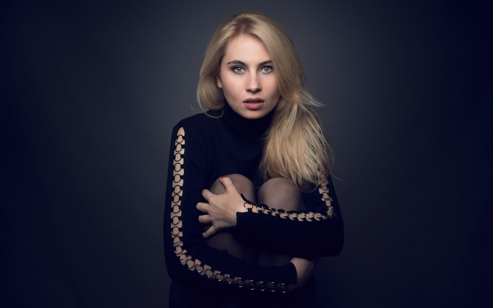 Блондинка в черном наряде на сером фоне