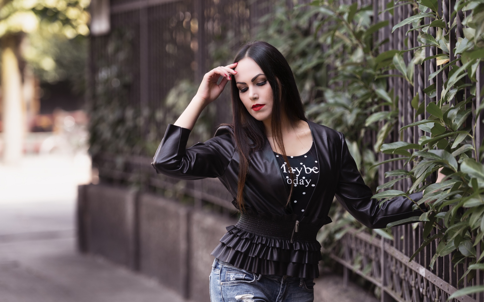 Длинноволосая брюнетка в черной куртке у забора