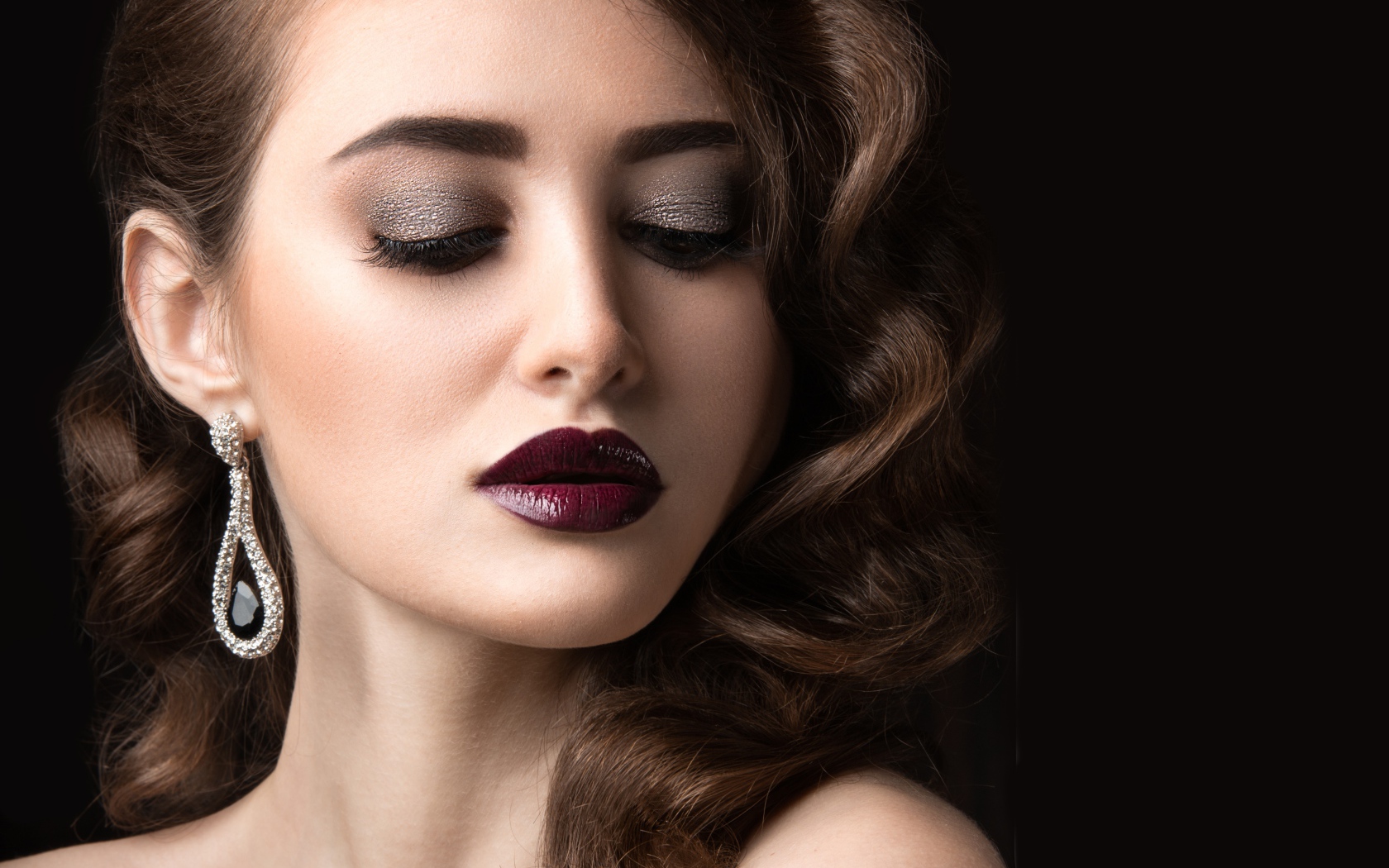 Длинноволосая девушка с ярким макияжем на черном фоне