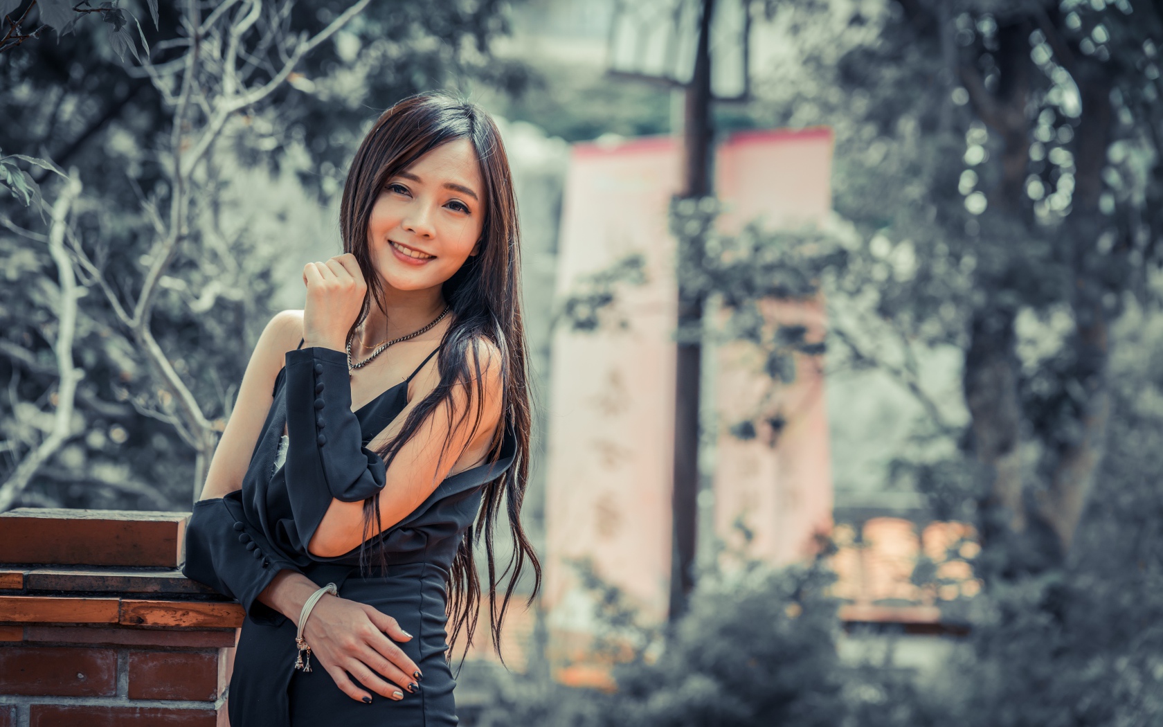 Улыбающаяся девушка азиатка в черном платье