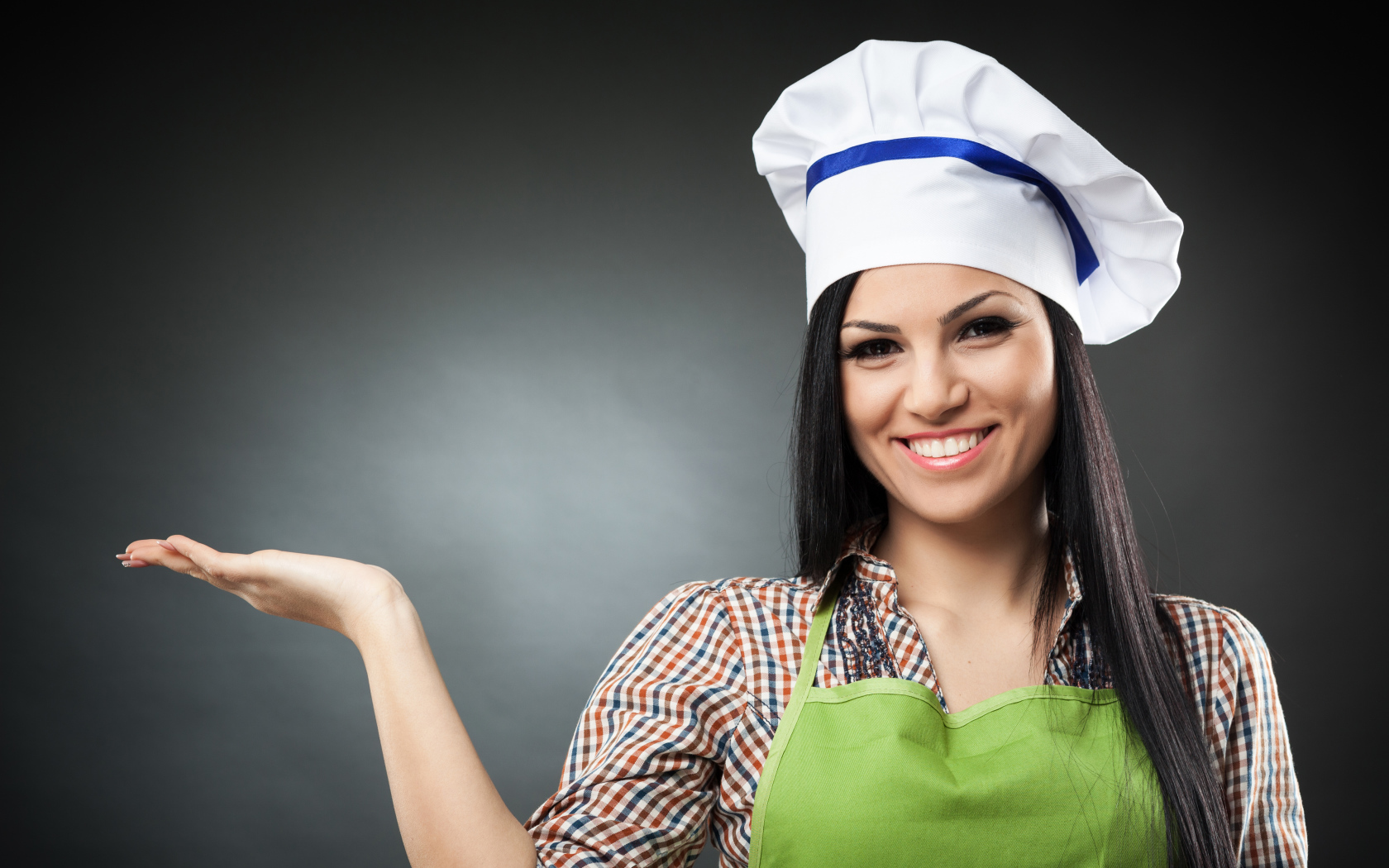 Улыбающаяся девушка в поварском колпаке на сером фоне