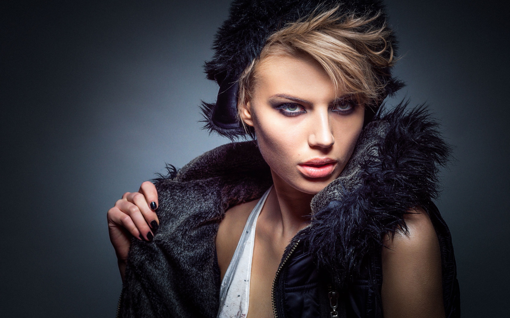 Девушка в теплой жилетке и шапке на сером фоне