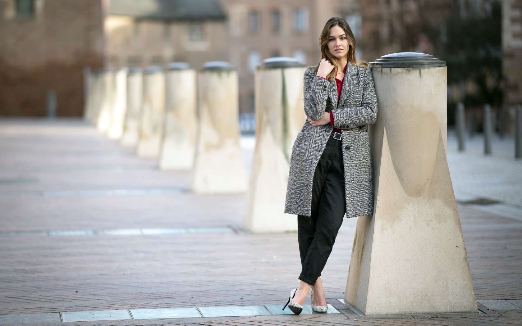 Девушка стоит в сером пальто 