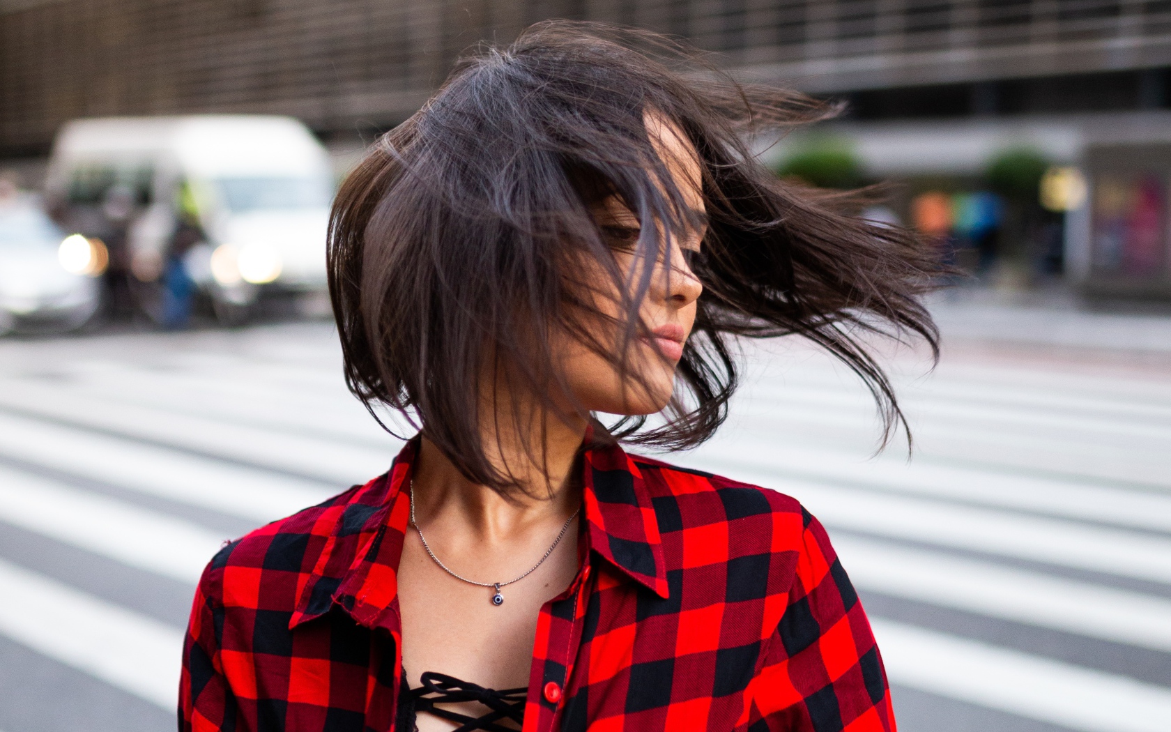 Ветер развивает волосы красивой шатенки в клетчатой рубашке